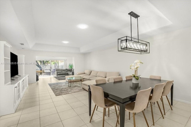 dining area with a tray ceiling, light tile patterned flooring, visible vents, and baseboards