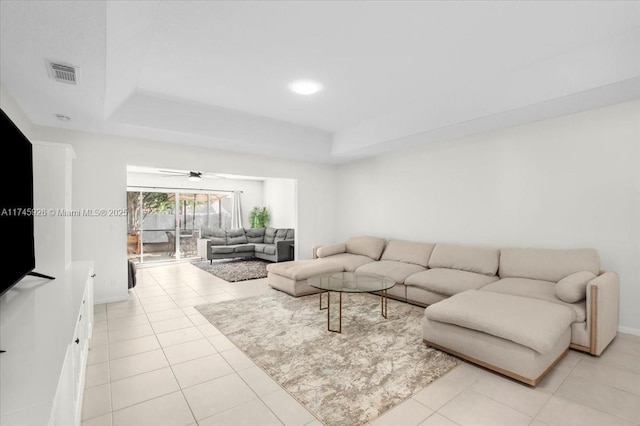 living area featuring light tile patterned floors, a tray ceiling, and visible vents