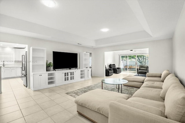 living room with light tile patterned floors and a raised ceiling