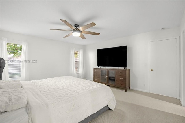 bedroom with light carpet, multiple windows, a ceiling fan, and baseboards