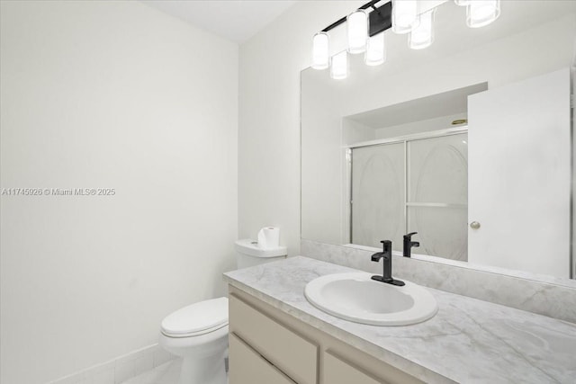 bathroom featuring toilet, a shower stall, baseboards, and vanity