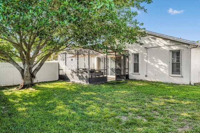 rear view of property with a fenced backyard, a lawn, and stucco siding