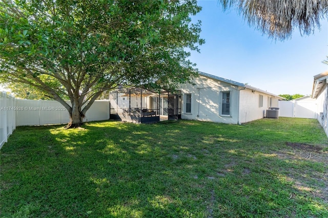 back of house featuring central AC unit, a lawn, a fenced backyard, and stucco siding