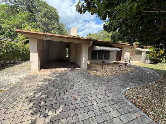 ranch-style home featuring a carport, decorative driveway, and stucco siding