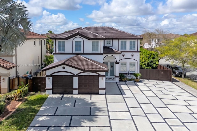 view of front of home featuring concrete driveway, a tile roof, fence, and stucco siding