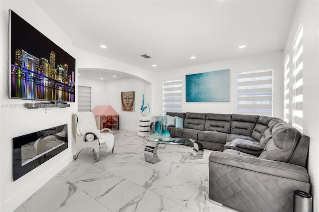 living room with arched walkways, marble finish floor, visible vents, and recessed lighting