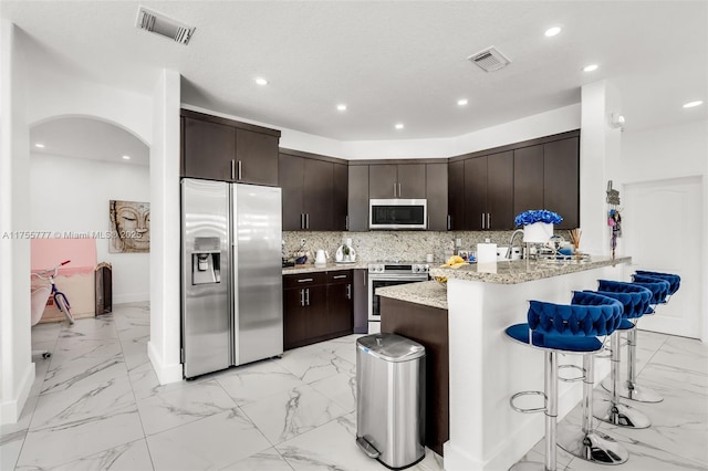 kitchen with a peninsula, visible vents, appliances with stainless steel finishes, and backsplash