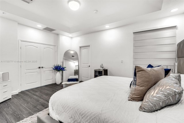 bedroom featuring arched walkways, dark wood-type flooring, and recessed lighting