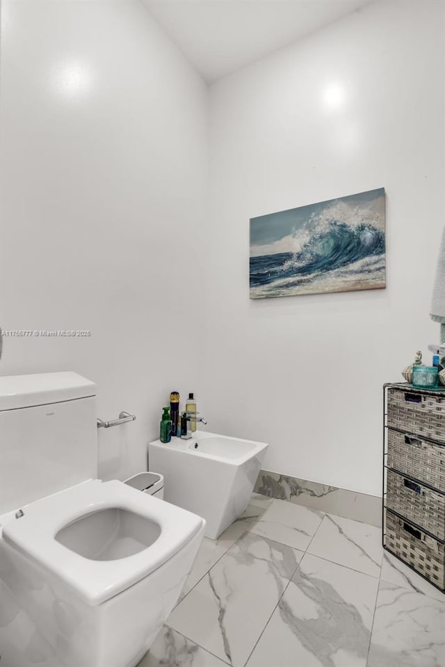 bathroom featuring marble finish floor, a bidet, and toilet