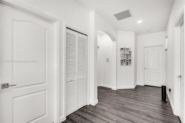 corridor with arched walkways, recessed lighting, visible vents, dark wood-type flooring, and baseboards