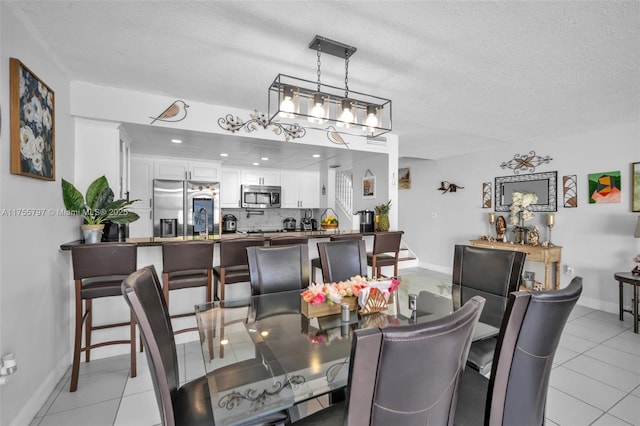 dining room with light tile patterned floors, baseboards, and a textured ceiling