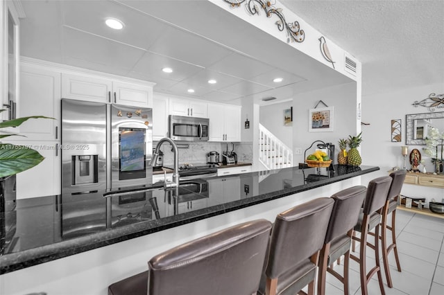 kitchen with white cabinets, tasteful backsplash, a breakfast bar area, and stainless steel appliances