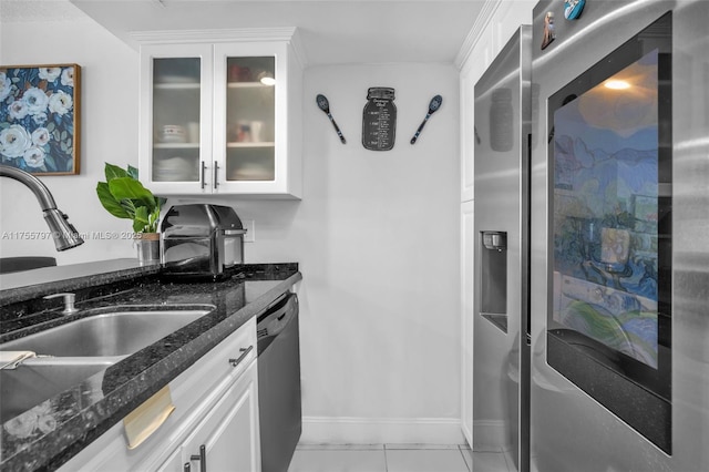 kitchen with stainless steel appliances, a sink, white cabinets, dark stone countertops, and glass insert cabinets