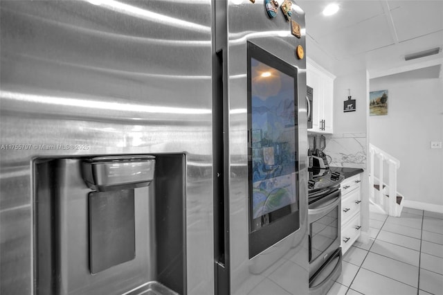 kitchen featuring light tile patterned floors, stainless steel appliances, visible vents, white cabinetry, and dark countertops