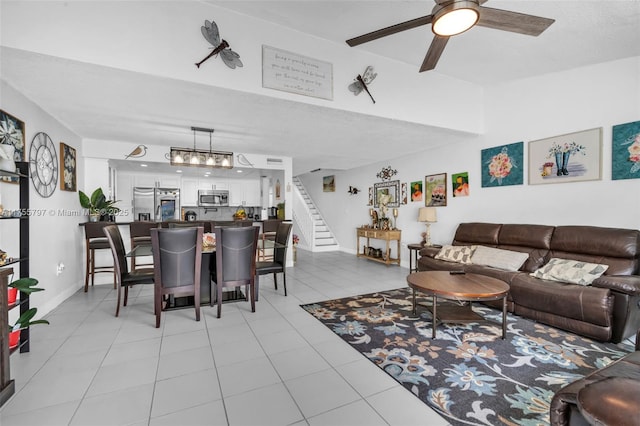 living room with light tile patterned floors, ceiling fan, stairway, and baseboards