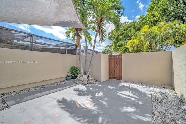 view of patio / terrace with a gate, fence, and a lanai