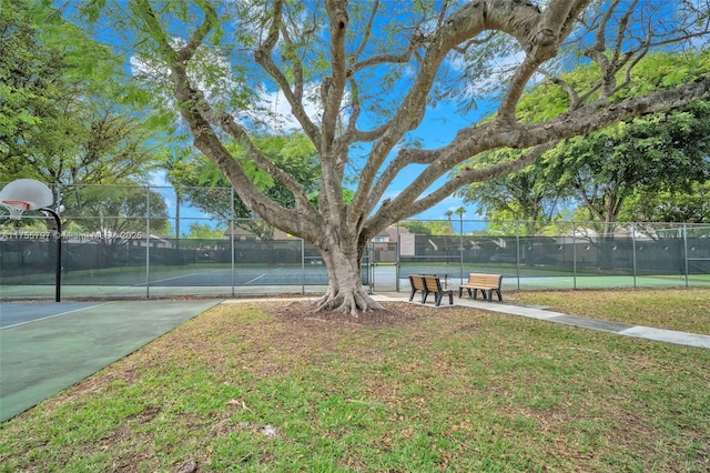 view of home's community featuring a tennis court, community basketball court, a lawn, and fence