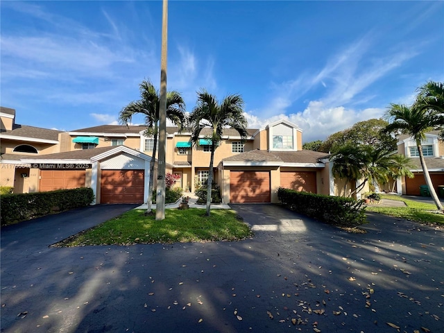 view of property featuring an attached garage, aphalt driveway, and stucco siding