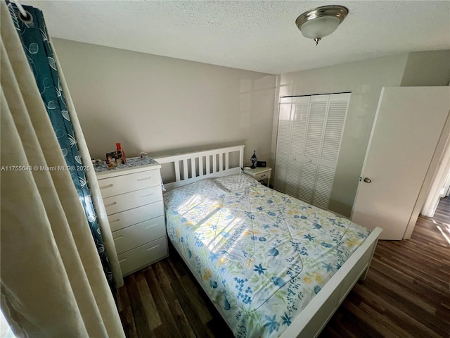 bedroom with a closet, a textured ceiling, and dark wood-style flooring