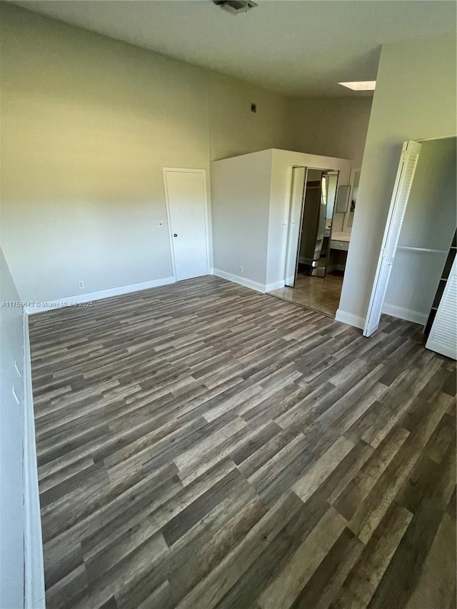 unfurnished bedroom featuring dark wood-style floors, visible vents, baseboards, and high vaulted ceiling