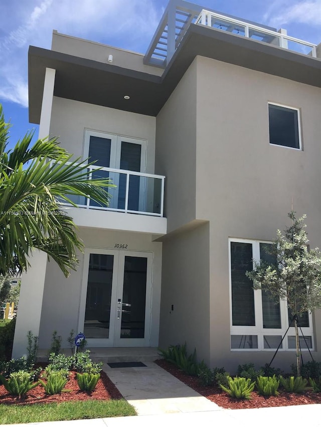 doorway to property featuring a balcony, stucco siding, and french doors