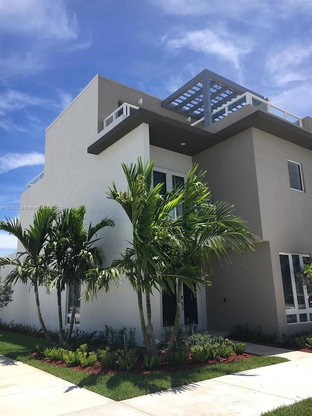 view of side of property featuring a balcony and stucco siding