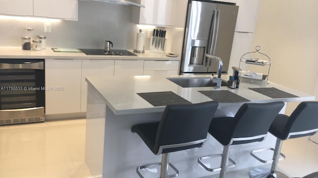 kitchen featuring black electric stovetop, white cabinets, beverage cooler, and stainless steel fridge with ice dispenser