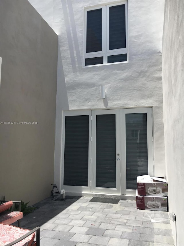 doorway to property featuring stucco siding, a patio, and french doors