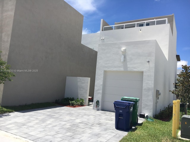 view of home's exterior with a garage, decorative driveway, and stucco siding