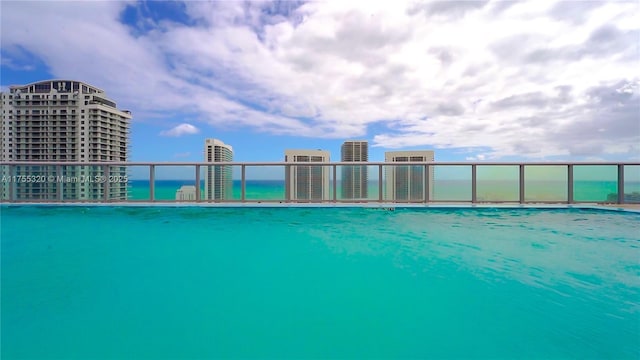 view of pool featuring a water view and a view of city