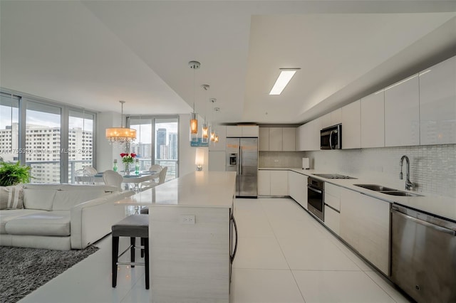 kitchen featuring stainless steel appliances, a sink, a kitchen breakfast bar, tasteful backsplash, and modern cabinets