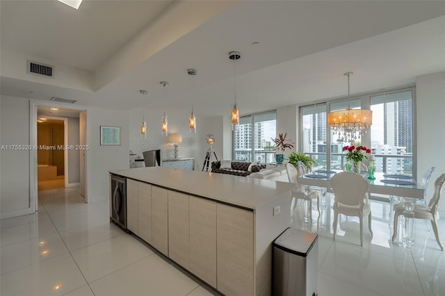 kitchen with light tile patterned floors, visible vents, a center island, hanging light fixtures, and light countertops