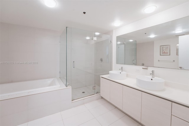 bathroom featuring a stall shower, a garden tub, a sink, and tile patterned floors