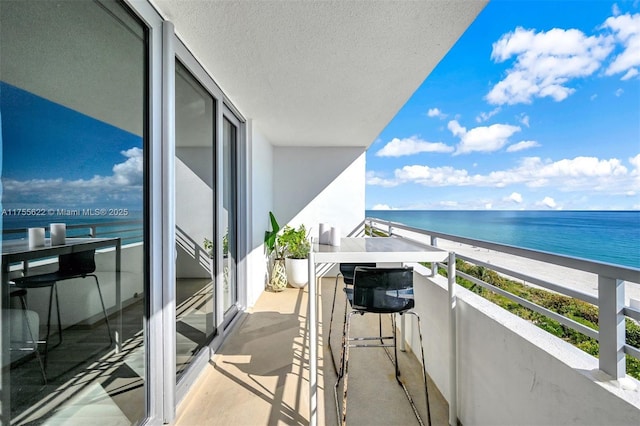 balcony with a water view and a view of the beach