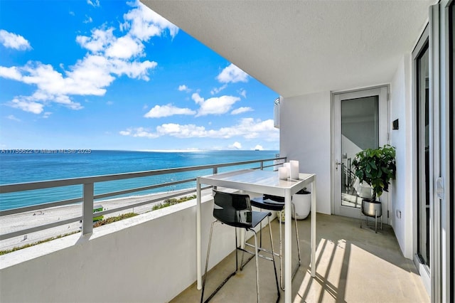 balcony with a water view and a view of the beach