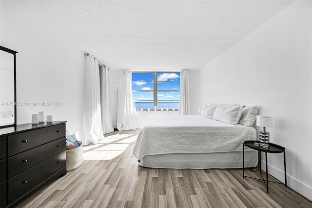 bedroom featuring expansive windows, a textured ceiling, and wood finished floors