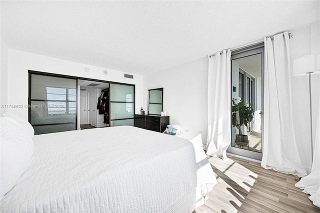 bedroom with visible vents, access to exterior, and wood finished floors