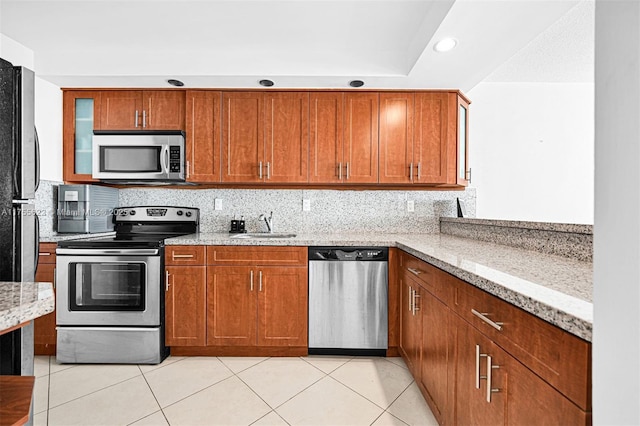 kitchen with a sink, appliances with stainless steel finishes, light tile patterned floors, and tasteful backsplash