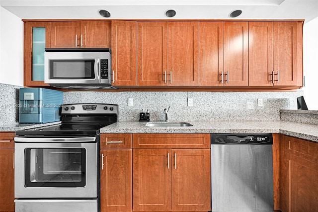5555 Collins Ave Unit 10M, Miami Beach, FL 33140 - kitchen with stainless steel appliances, light stone countertops, brown cabinets, and tasteful backsplash