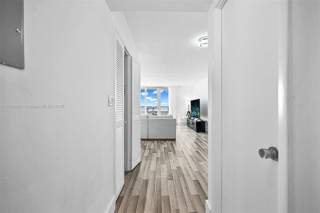 corridor featuring baseboards, a textured ceiling, and wood finished floors