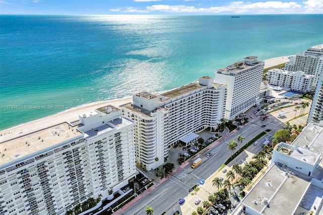 drone / aerial view featuring a water view, a view of the beach, and a city view