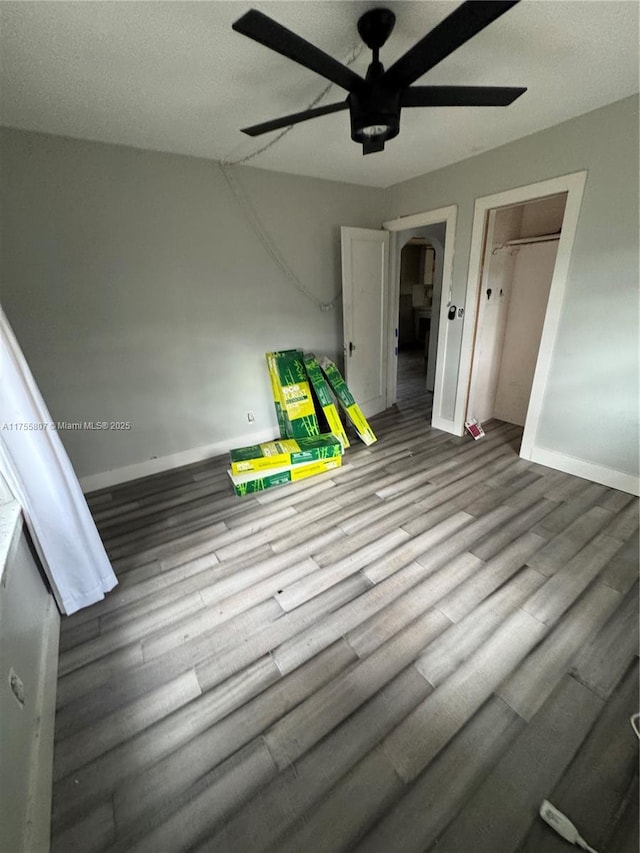 spare room with a ceiling fan, baseboards, and wood finished floors