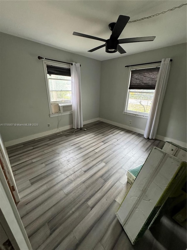 empty room with a ceiling fan, baseboards, and wood finished floors