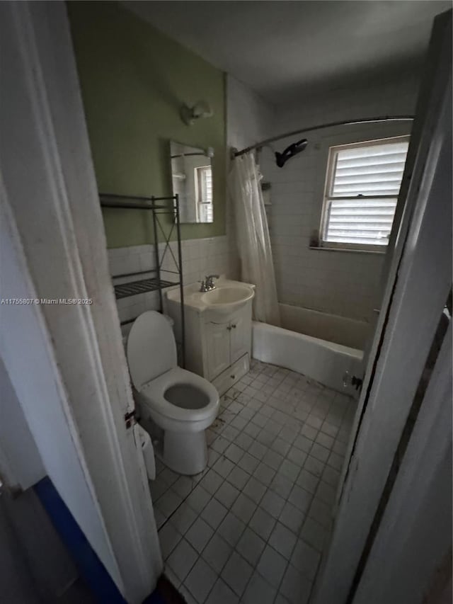 full bath featuring toilet, a wainscoted wall, vanity, tile walls, and tile patterned floors