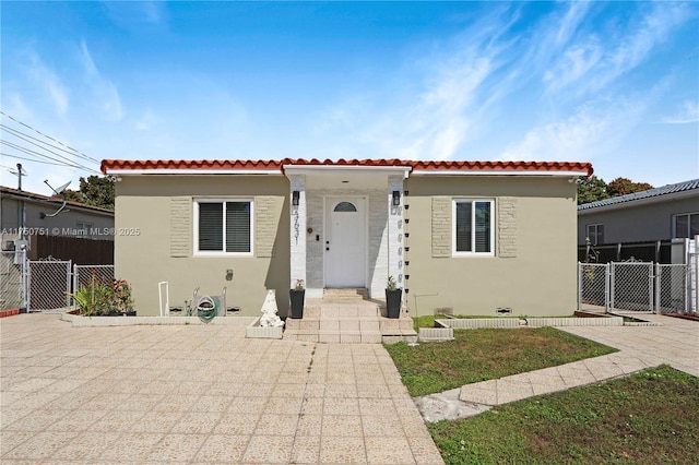 mediterranean / spanish home with a gate, fence, and stucco siding