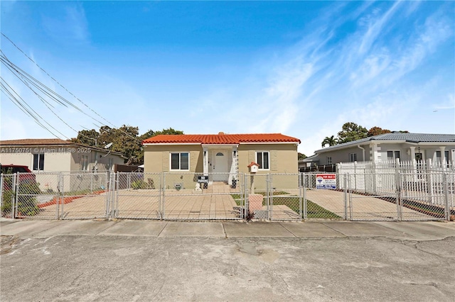 view of front of property with a fenced front yard, a gate, a tile roof, and stucco siding