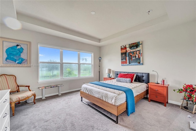 bedroom with a raised ceiling, light carpet, and baseboards