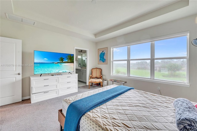 carpeted bedroom with ensuite bath, radiator heating unit, visible vents, and a raised ceiling