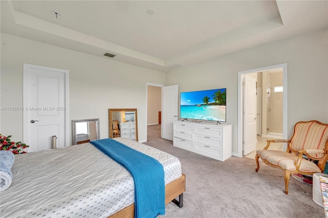 bedroom featuring a tray ceiling, visible vents, and light colored carpet