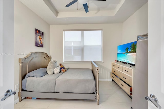 bedroom featuring ceiling fan, a tray ceiling, and baseboards